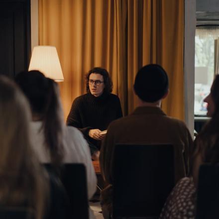 An author engaging with an audience during a book discussion in a cozy indoor setting.